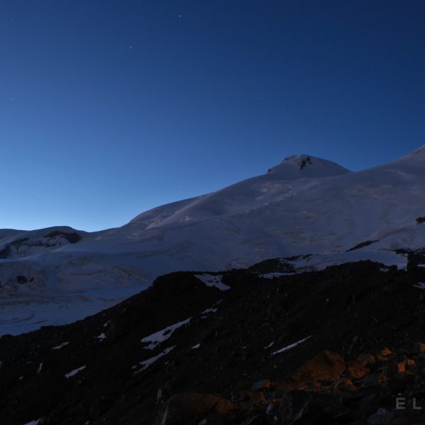 Twin summits in Russia at dusk revealing a starry bluish sky with a rock glacier in the foreground