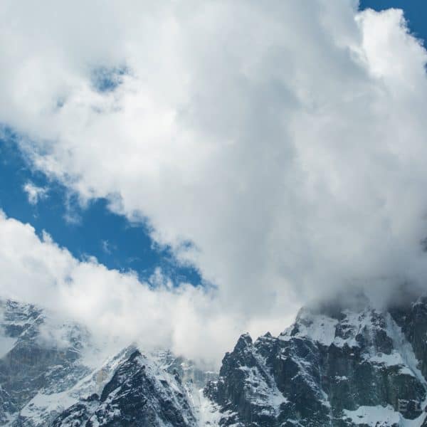 Clouds form over a Himalayan snow capped peak with a deep blue sky