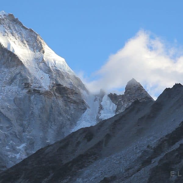 A triangular summit peak with a rocky glacier in the foreground near Mt Everest