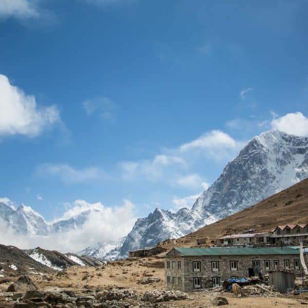 Stone hotels with colorful roofs in a valley in Nepal with mountains in the distance