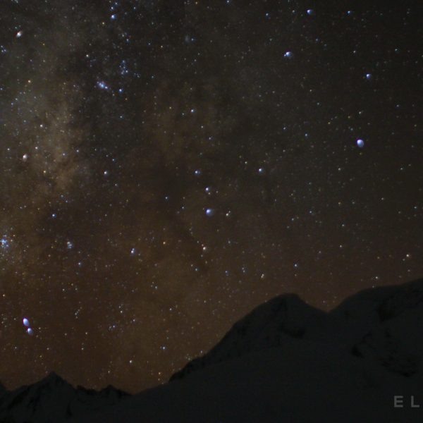 Sky of stars with the milky way next toimpressive snow capped peaks