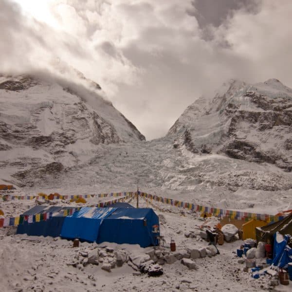 Multi colored tents on a snowy glacier in the Himalyas with mountains in the distance near Mt. Everest