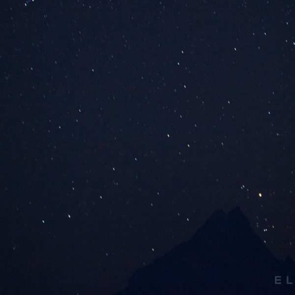 Two Himalayan mountains in the distance with a sky filled with stars at night