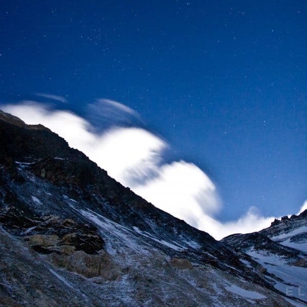 Highest mountain in the world at night from below with stars and clouds high above in the sky