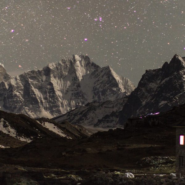 Stone house in the mountains in Nepal in a valley with stars in the background