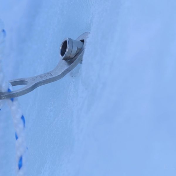 Close up shot of an ice screw with a rope being passed through it