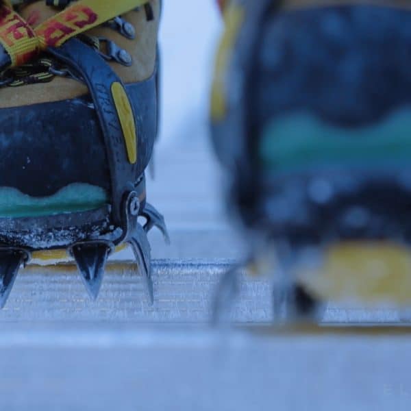 Close up of yellow boots walking on an aluminum ladder in a snowy setting