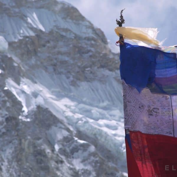 A large multi colored prayer flag in front of a snow capped mountain