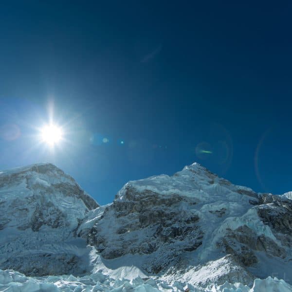 Sun rising above a mountain at Everest basecamp with a large glacier in the forground leading up towards the summit behind one of the peaks